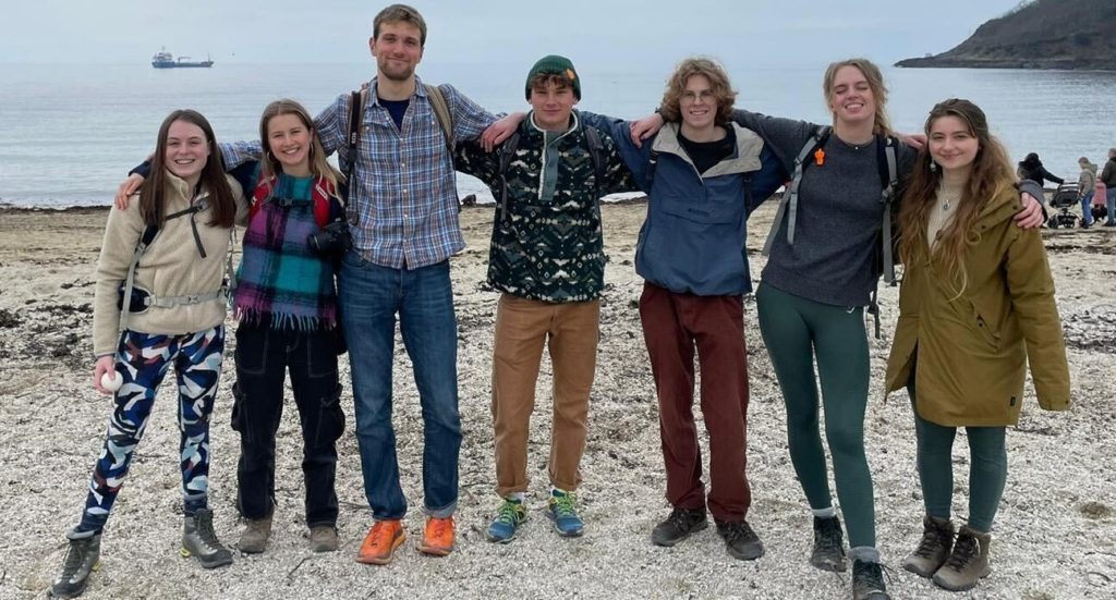 Seven students on a beach in walking gear