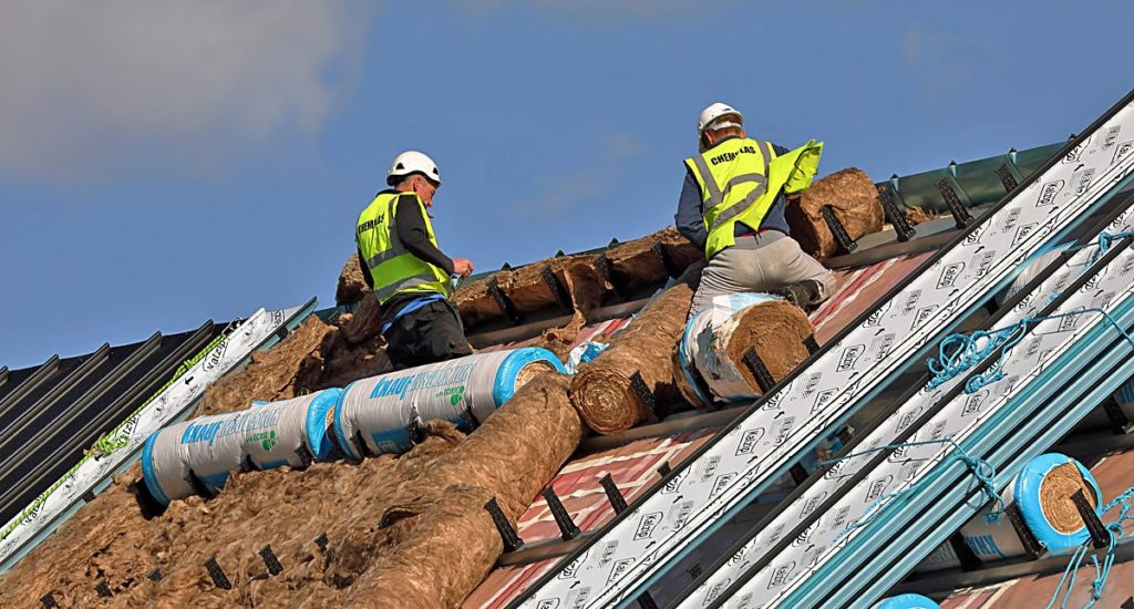 Two workers on a roof, installing insulation