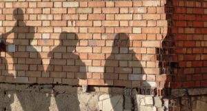 The shadows of several people seen on a brick wall