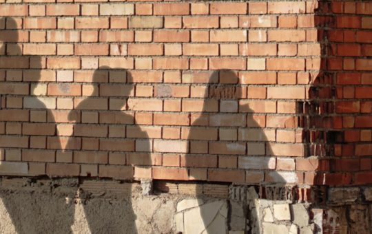 The shadows of several people seen on a brick wall