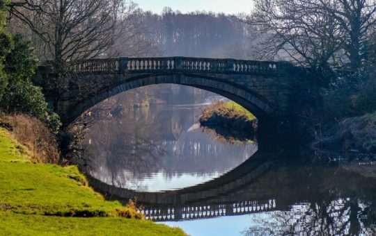 A stone bridge over a calm river
