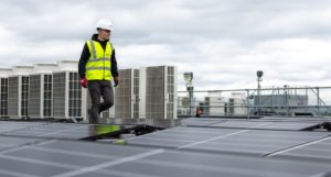 A worker on a rooftop among solar panels