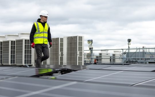 A worker on a rooftop among solar panels
