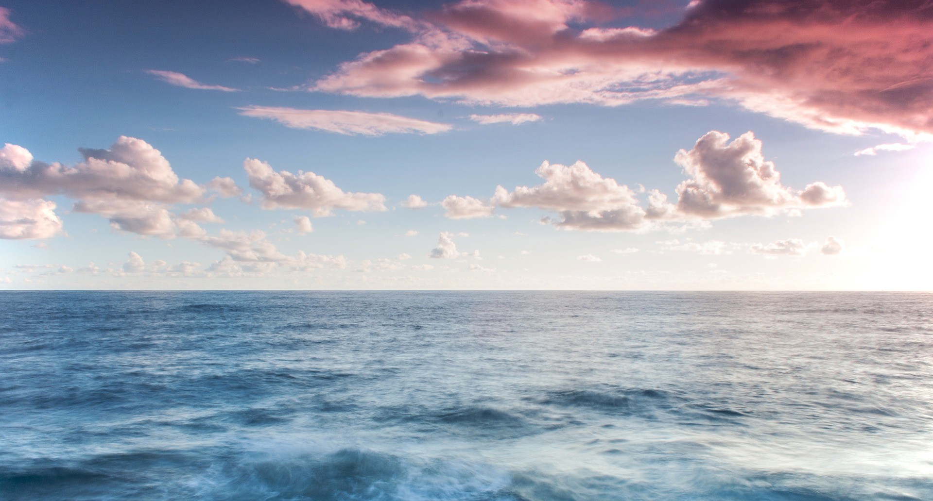 An image taken at sea, with clouds visible over calm waters