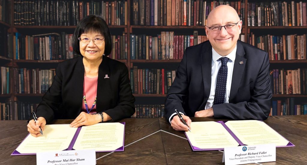 Two people sit at a desk signing forms