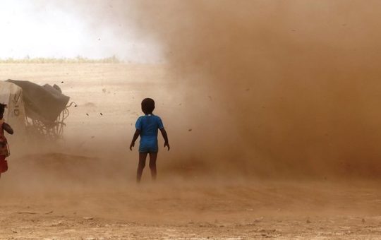 Two children in a dust storm in an arid landscape