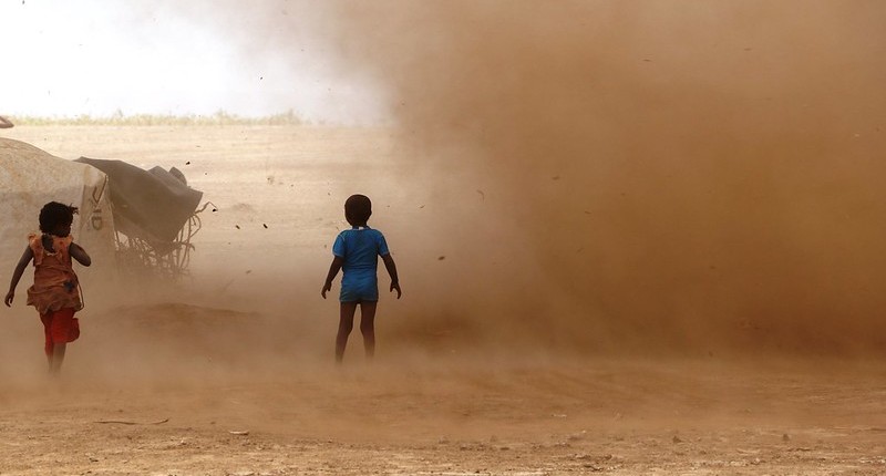 Two children in a dust storm in an arid landscape