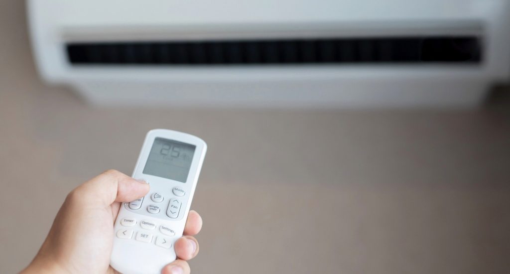 A hand holding the controller for an air conditioning unit