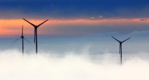 Wind turbines standing above low clouds or mist