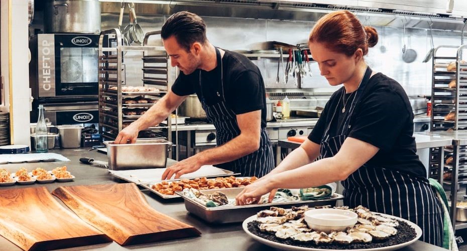 Man and Woman Wearing Black and White Striped Aprons Cooking