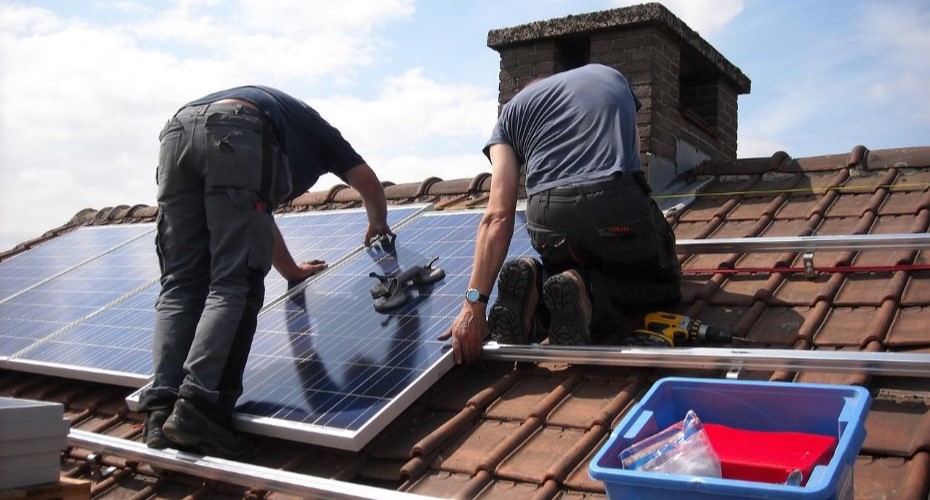 Two workers on a roof fixing solar panels