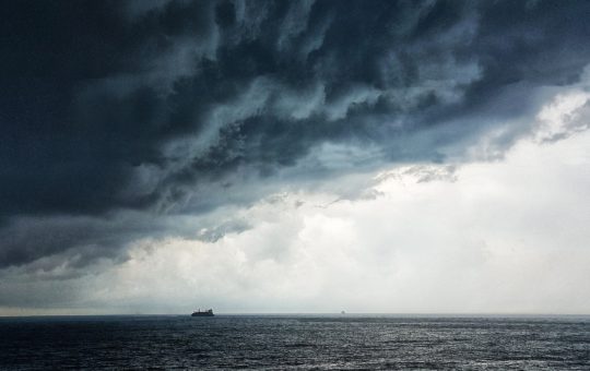 A ship at sea, with storm clouds overhead