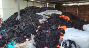 A large pile of discarded wetsuits in a warehouse