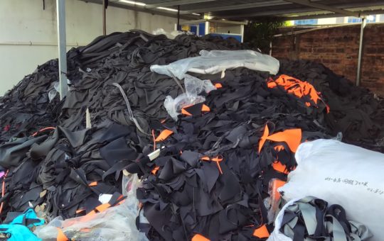 A large pile of discarded wetsuits in a warehouse