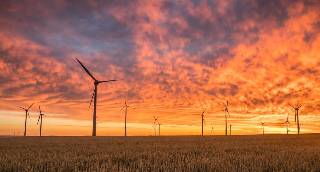 Wind turbines seen against a red/orange sky at dawn or sunset