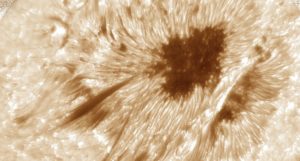 The surface of the sun seen in swirling pale yellow and black, with an obvious dark area towards the top right of the image
