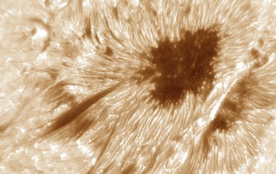 The surface of the sun seen in swirling pale yellow and black, with an obvious dark area towards the top right of the image