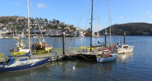 Small boats seen in a harbour, with a town or village in the background