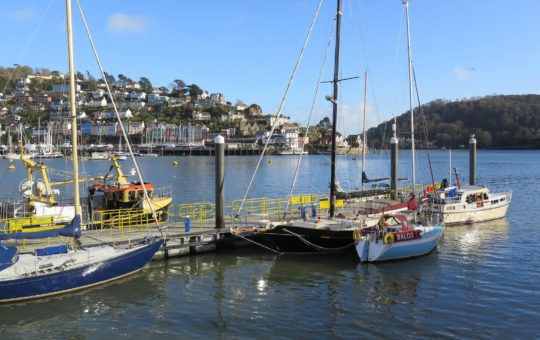 Small boats seen in a harbour, with a town or village in the background