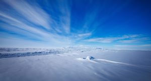 An icy landscape in Antarctica under blue skies with thin streaks of cloud
