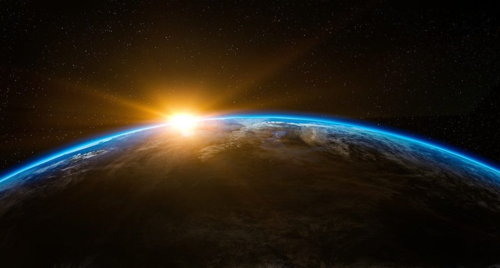 Earth seen from space, with the sun just visible at the top