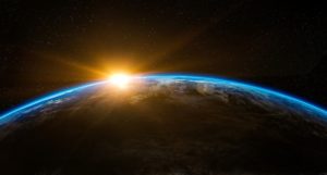 Earth seen from space, with the sun just visible at the top