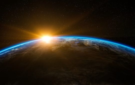 Earth seen from space, with the sun just visible at the top
