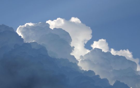 Clouds of varying whiteness/darkness with blue sky visible behind