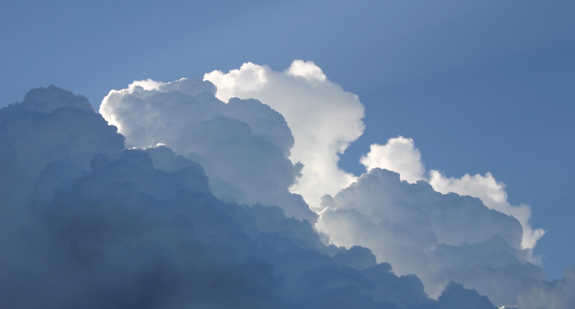 Clouds of varying whiteness/darkness with blue sky visible behind