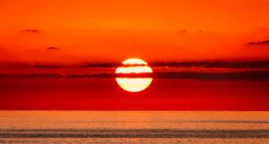 The sun setting in deep orange and red colours over the ocean