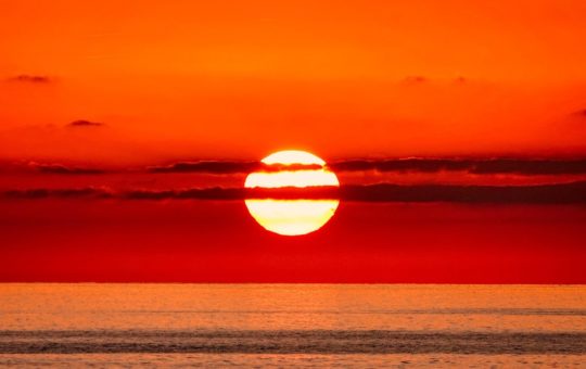 The sun setting in deep orange and red colours over the ocean