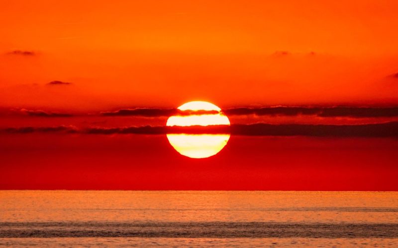 The sun setting in deep orange and red colours over the ocean