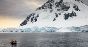A small boat in the sea, with a snow-covered mountain visible in the background
