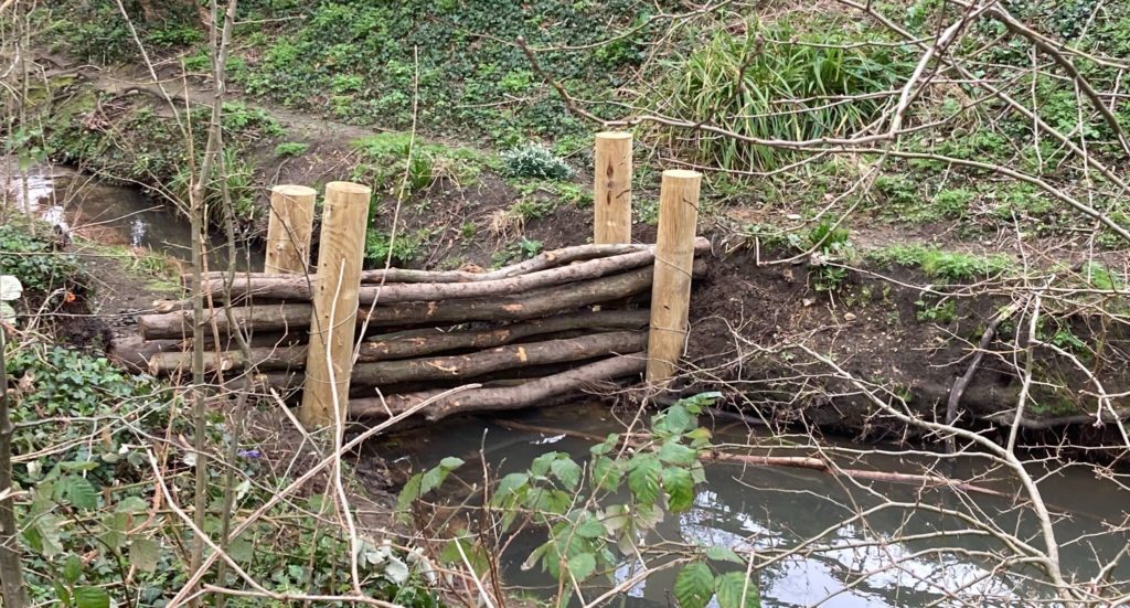 A dam in a small stream, made of long sticks/logs held up for our corner posts