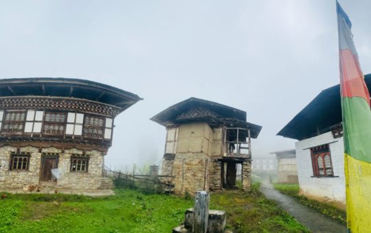 Three empty houses on a misty hill