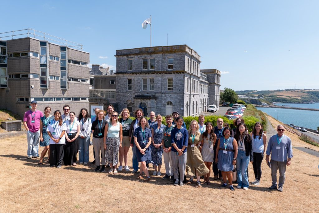 A group of people lined up in sunshine for a photo outside the MBA in Plymouth