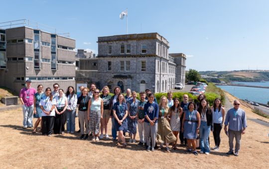 A group of people lined up in sunshine for a photo outside the MBA in Plymouth