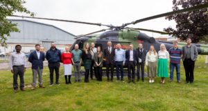 A group of people standing in front of a helicopter on a lawn