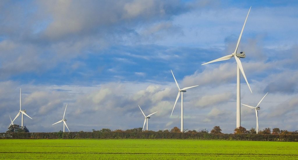 Wind turbines in green fields, with blue sky and clouds above