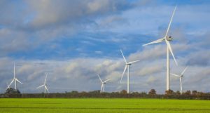 Wind turbines in green fields, with blue sky and clouds above