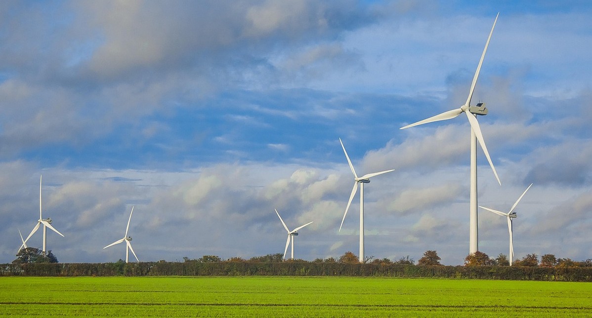 Wind turbines in green fields, with blue sky and clouds above